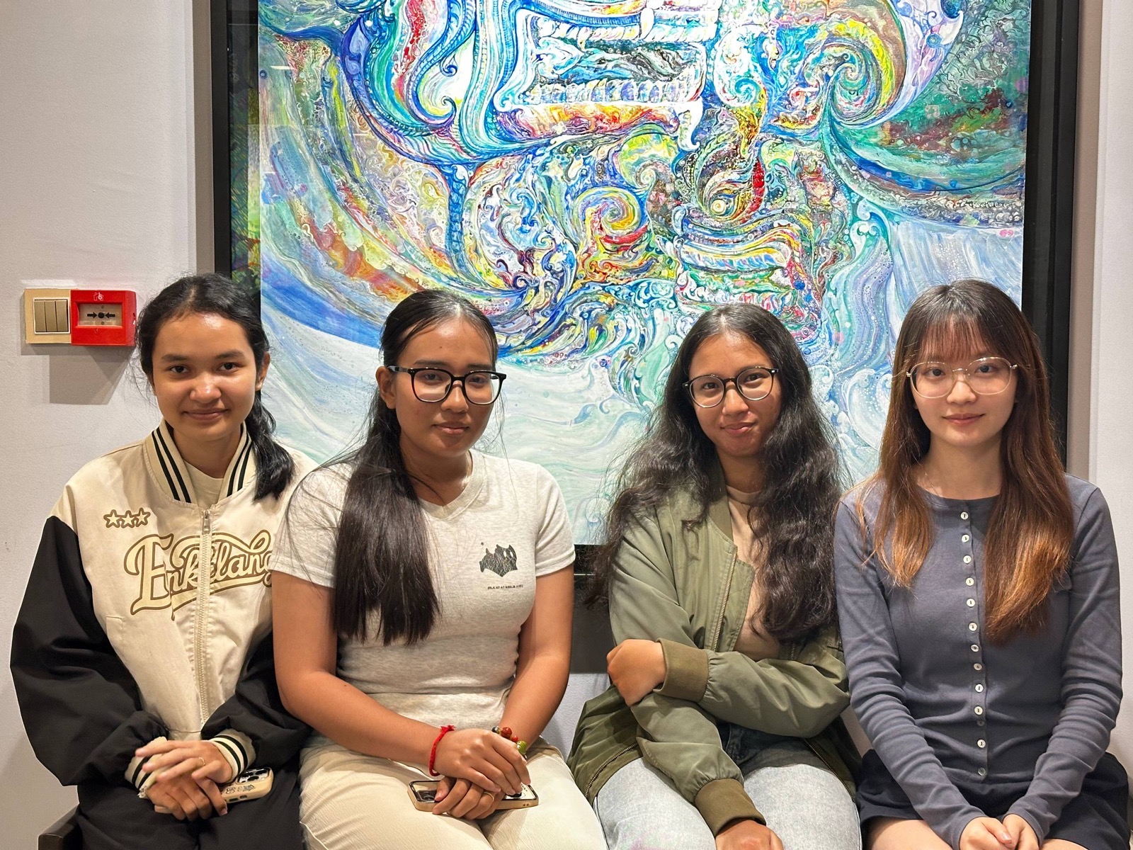 The Artisity team, four of us seated in front of a colorful painting